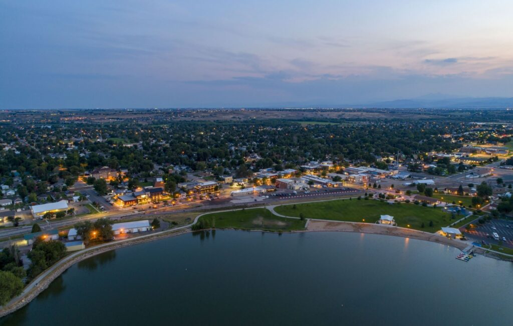 Windsor | rcastlemortgage.com Aerial view of Windsor, Colorado at dusk, showcasing the town's skyline illuminated by evening lights. Great place for homeowning. Get a quote from Robert Castle Mortgage today.